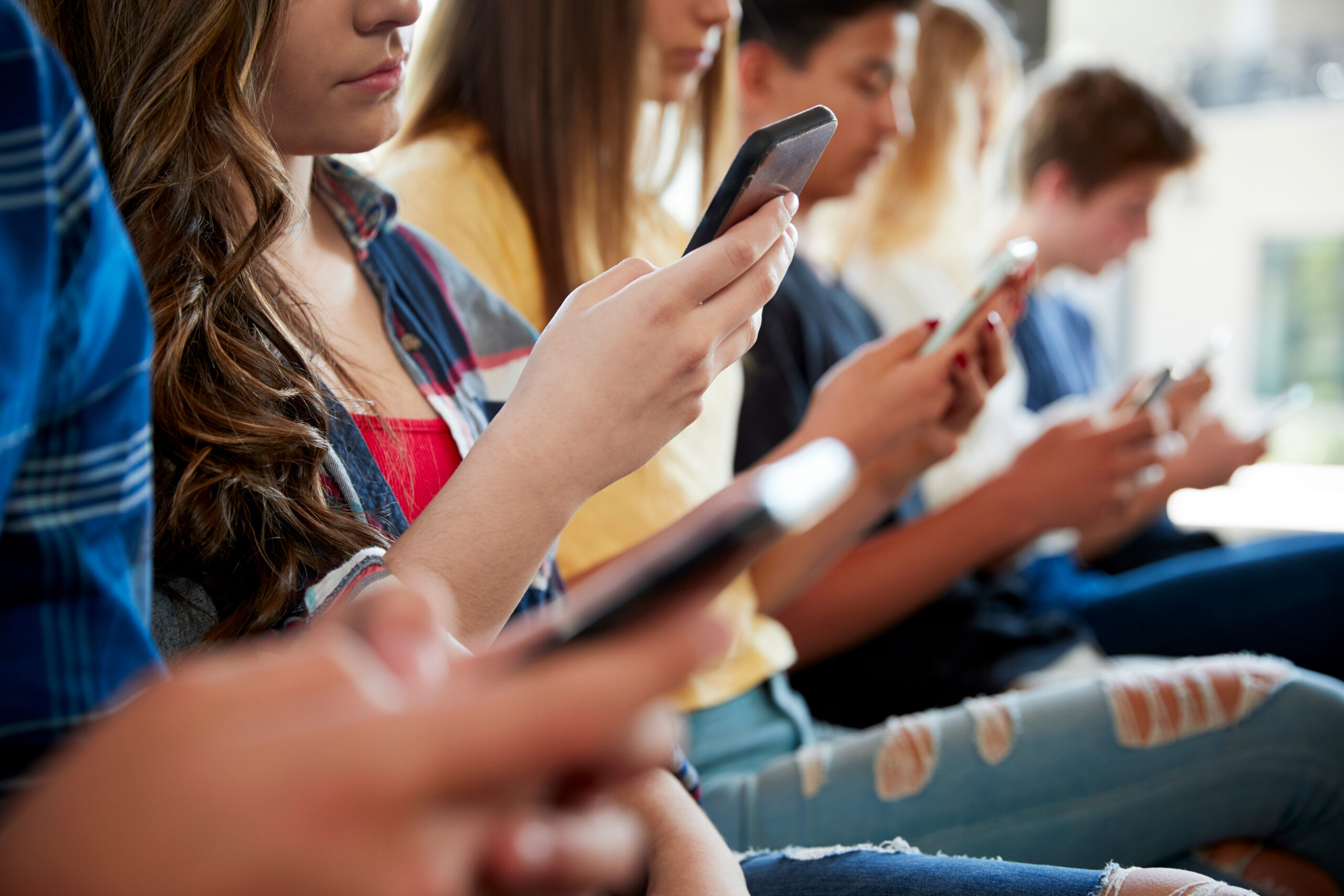 A group of teens spend time on their smartphones.